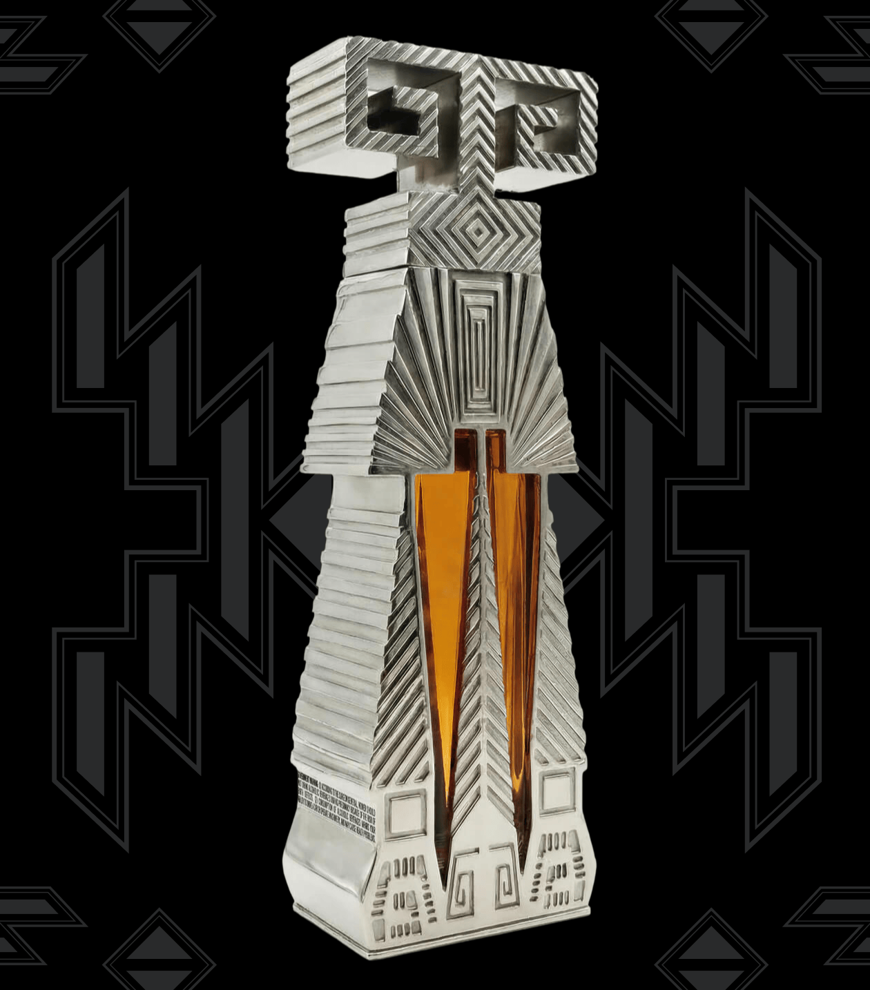 An abstract, sculptural perfume bottle with a silver-toned geometric design and two vertical amber glass necks, centered on a black background with dark gray Art Deco-style motifs.